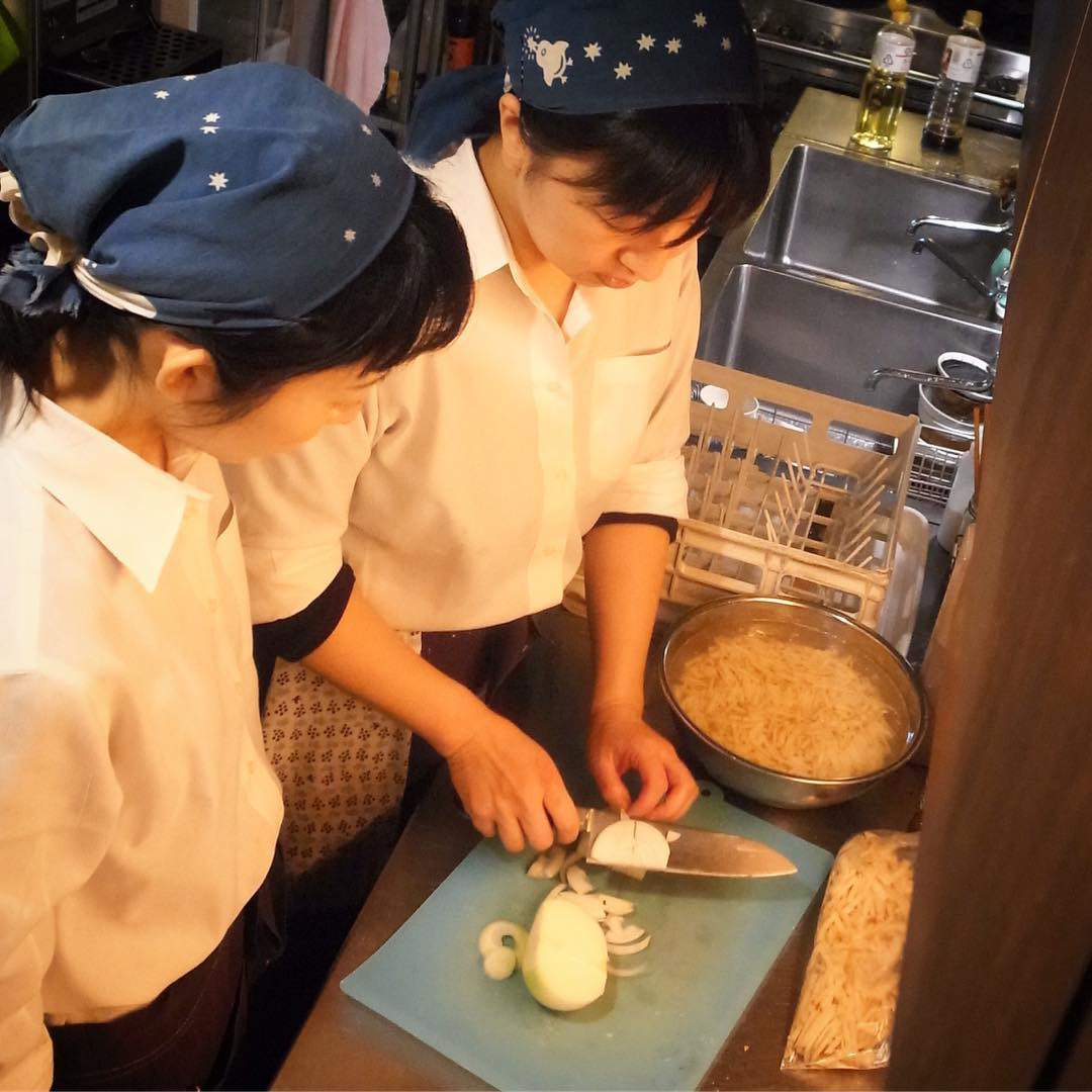 キッチン二人体制はさらに少数精鋭のチーム作りと、以前から仕込みの手伝いもお願いしておりますホール係の南ちゃん、店長ミヤザキからチヂミの具の切り方を教わっております、よろしくお願いします（笑）（お）