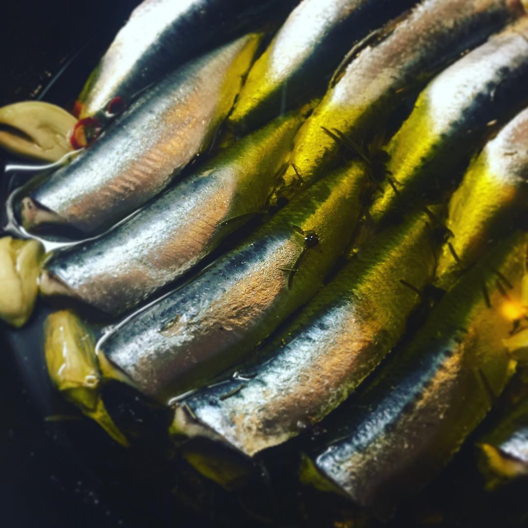 イワシと新じゃがいものコンフィ、
美味しく煮えてますよ！
ピチピチのイワシをさばいて、塩水漬けにしてから、オリーブオイルでコトコト煮ています。ニンニクとブラックペッパー、ローズマリーで香りよく風味よく、じゃがいもと一緒に食べるのが決まりです。気分はスペインのバルかな！行ったことないけど。okayanは行ったことあると思いますよ、ええ。白ワインでいくか、ビールで行くか、スッキリ系日本酒に合わせても良いね！（麻）