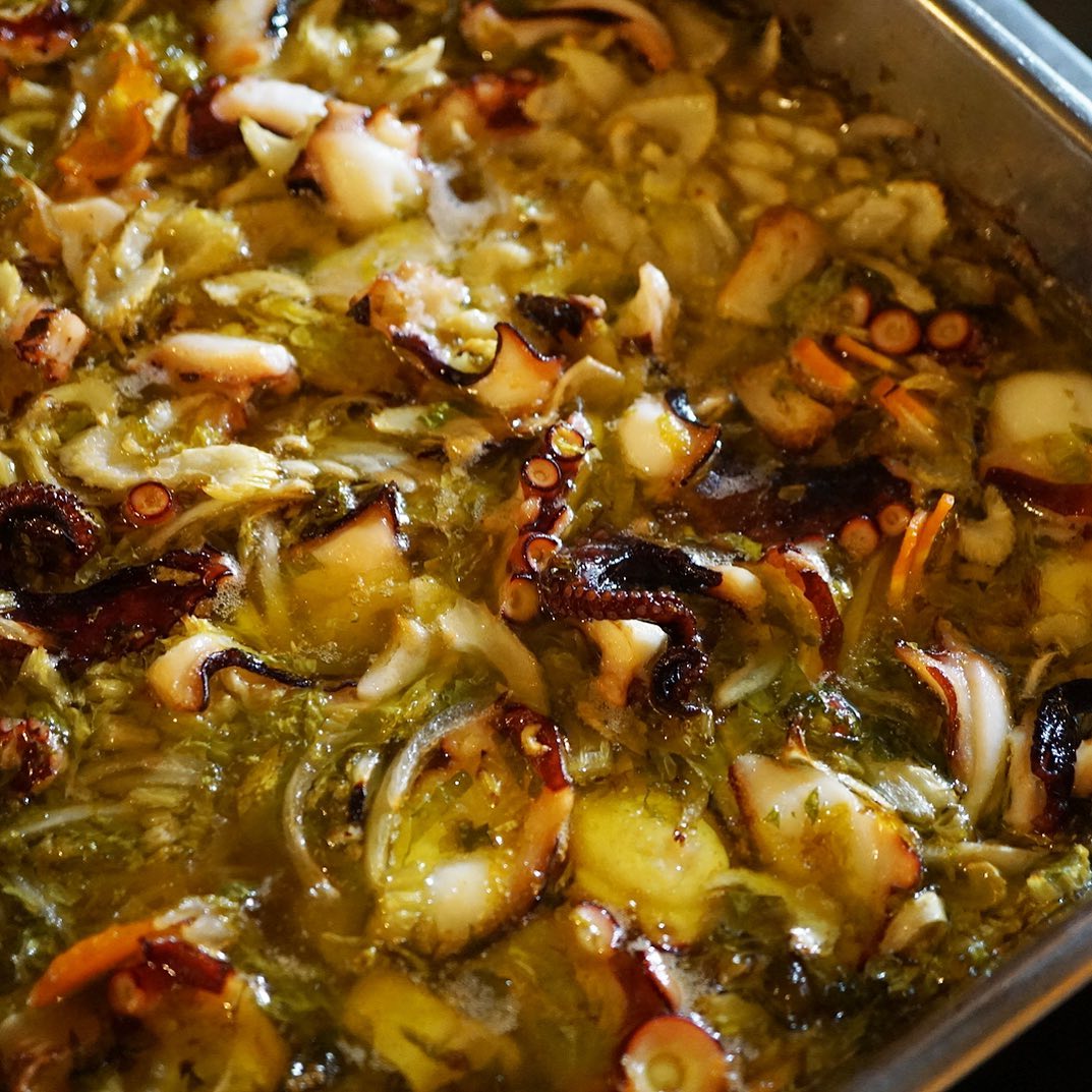 さてとすでにすっかり店長ミヤザキもお気に入り！新メニューは「タコとじゃがいものオリーブオイル焼き」！まずはこうしてバットににんにくセロリなどなど香味野菜と合わせてオリーブオイルはたっぷりで、オーブンで焼いてしまうのです！…ってここに別にグリルしたじゃがいもをあわせます！いや、この時点で充分おいしそう！（お）