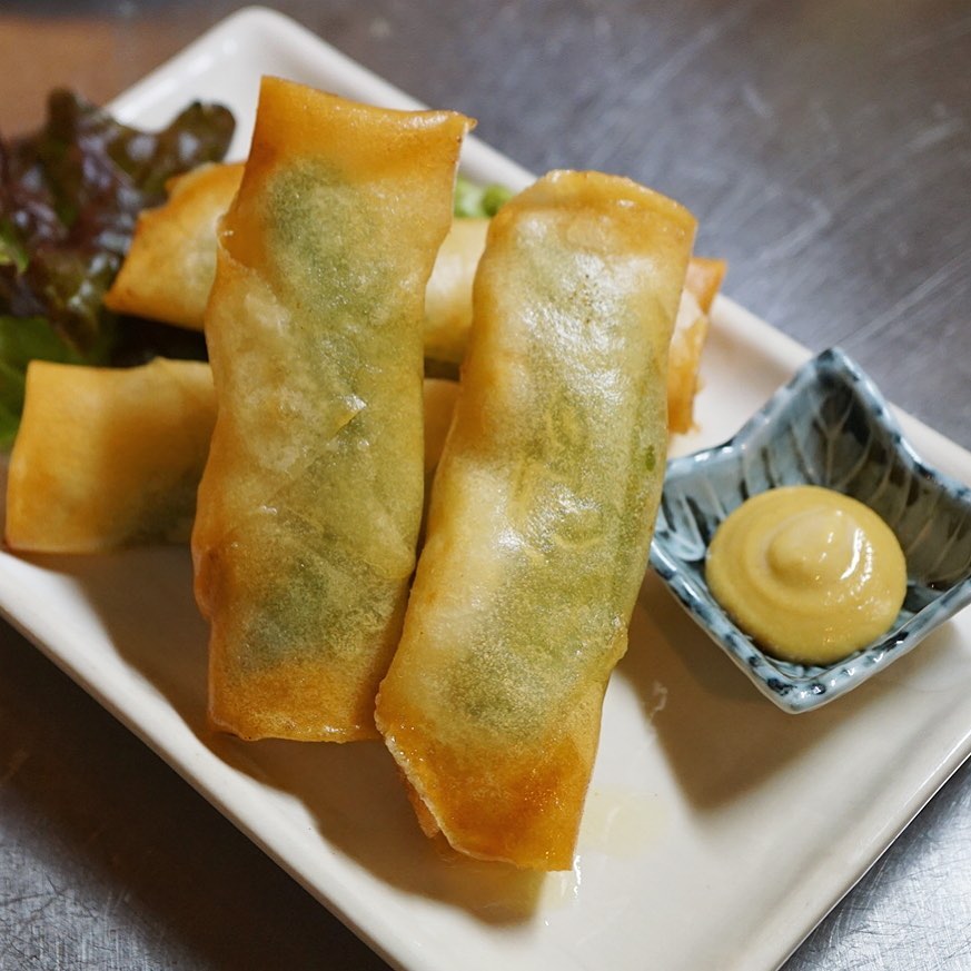 さてと年明け新作揚げ春巻は「エビとスナップえんどうの揚げ春巻」！ぷりぷりエビのおいしさに、スナップえんどうはさやのまんままるまるひとつ皮で包んで…って、うっすらその姿が皮越しに見えるでしょ？（笑）あつあつをからし醤油で！（お）