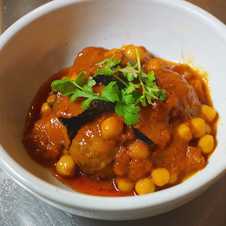 見たことあるような新メニュー！　明日、火曜日のランチにも登場します「肉だんごとひよこ豆のスパイストマト煮込み」！ひよこ豆をコトコト煮てホクホクに仕上げましたら、トマトソースをベースに、クミンやコリアンダー、シナモンにチリペッパーで優しいスパイス風味で、ほどよい刺激に。カレーじゃなくて、あえてのスパイストマト味は、元気になれる味ですよ〜（麻）