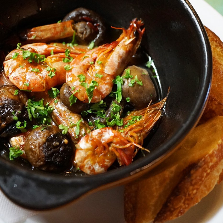 さてと五輪も開幕して土曜日…ぷりぷりおつまみは「えびときのこののアヒージョ」！殻付きエビの旨味！きのこと合わせたらにんにくの風味いっぱいオリーブオイルで煮たアヒージョ！バケットを添えて（お）