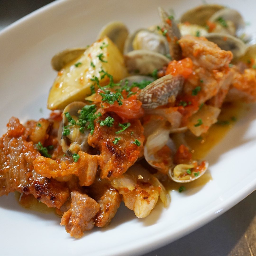 今週は、ほんのりポルトガル方面に参ります！　「豚肉とアサリのポルトガル風蒸し」は、パプリカペーストに漬け込んだ豚肩ロース肉とアサリを蒸し焼きにして、旨味on旨味の絶対美味しいやつに！フライドポテトも入れて旨味を吸わせていただきます。店長ミヤザキもぜひ持ち帰りたい一品です（麻）