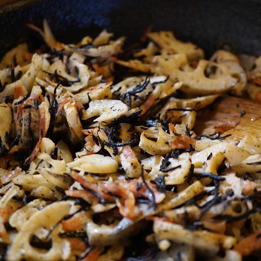 ざくざく大きな中華鍋に出来上がっておりますのは「れんこんとひじき、ベーコンのナンプラー炒め」！って、いや、食材の方向性も味付けもなんだかてんでバラバラ？もこれが思いがけず見事なチームワークで和風も洋風もエスニックも超えてしっかりおいしいお惣菜！（笑）ごはんにお酒のアテにもうってつけ！まだの方はぜひ一度お試しくださいな〜！（ってオレってなんにも言ってねー…笑）（お）
