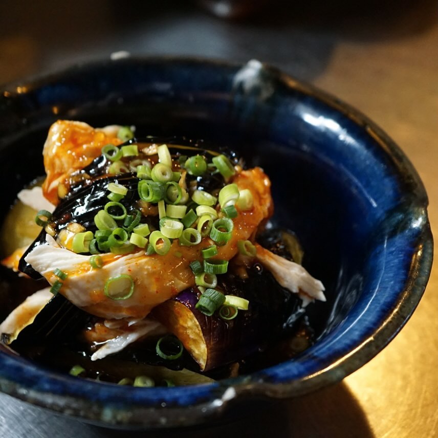 オイスターソースと黒酢をベースに香味野菜を混ぜ込んだ、中華風の冷製だれ「リャンパンだれ」で、春茄子を美味しくいただくおつまみ作りました！
蒸し鶏と揚げ茄子のリャンパンだれ！
これまでリャンパンだれといえばリトスタではリャンパン豆腐、豆腐の上にあげた茄子を乗っけてタレをかけたものをお出ししておりましたが、より酒の肴、よりごはんのおかずにもなる一品として登場しております！
あつあつ柔らかく甘みのある揚げなすと、しっとり蒸しあげた鶏肉を合わせて、旨みの塊みたいなお惣菜になっております。
この週末、ひとつお試しを！（麻）