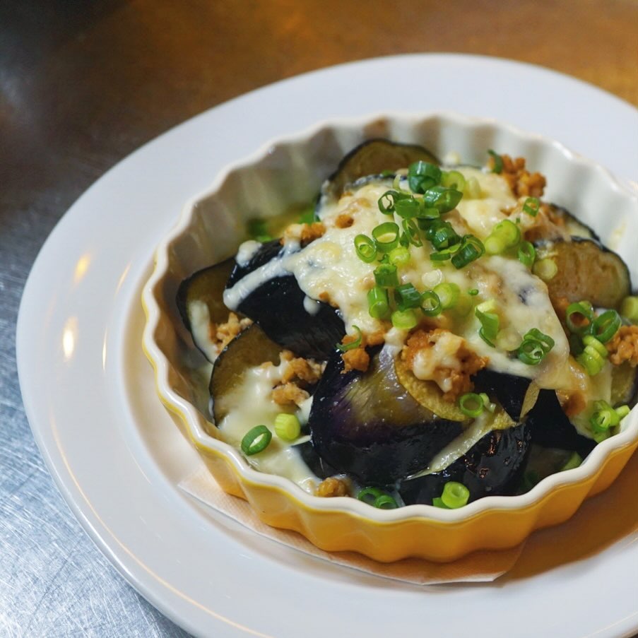 三鷹産の茄子も美味しい季節になってきましたね♪ ビールにもワインにも日本酒にも、もちろんごはんにもあう「茄子と味噌そぼろのチーズ焼き」お出ししてますよー！
味噌そぼろは豚ひき肉を酒煎りして余分な脂を抜き、生姜しっかりめの配合で味噌味にしています。チーズと合わせると、和風のような洋風のような、さっぱりグラタンといった面持ち。
今週末の夜は、本日金曜日と日曜日にお席の余裕がございます！お電話お待ちしております☆（麻）