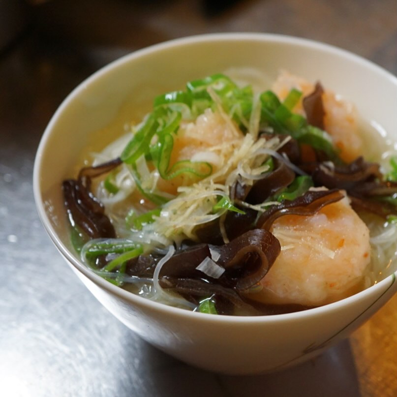新年の新メニュー！　お正月に暴飲暴食したワタクシ的には、優しい味のあったかいもの食べたい…ということで、実に今店長ミヤザキが食べたいもの作りました、「えびだんごの汁ビーフン」！
そもそも汁ビーフンというものが好きなんだよな…でもあまりお目にかからない。昔、南阿佐ヶ谷にあった頃の馬さんのお店、潮州で衝撃的に美味しい汁ビーフン食べたなあ…なんて思い出しつつ、鶏がらをコトコト3時間煮込んでスープをとって、エビは生姜汁で隠し味を入れてミンチにしてエビ団子に。キクラゲの食感とねぎの風味、短めの針生姜をのっけて優しさの中にメリハリのある味わいに仕立てました。
あくまで優しい、でもちと気が利いている、を目指した汁ビーフン。出なかったらやめちゃうよ！ということでぜひ優しさに浸りに来てくださいね♪（麻）