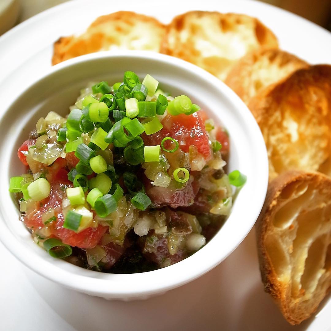 金曜日〜！と今夜のビールのおともは新メニューの「まぐろのタルタル風」！しっかり旨味のまぐろとたまねぎ、ピクルス、青じそに黒オリーブなどなどみじん切りにして合わせたら、かりかりバケットにのっけてさくさくどうぞ！クセになるおいしさですよ！（お）